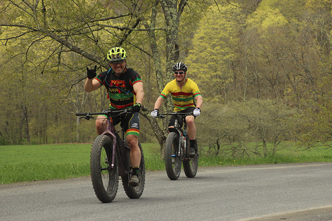 Two cyclists, one with fat bike giving a salute