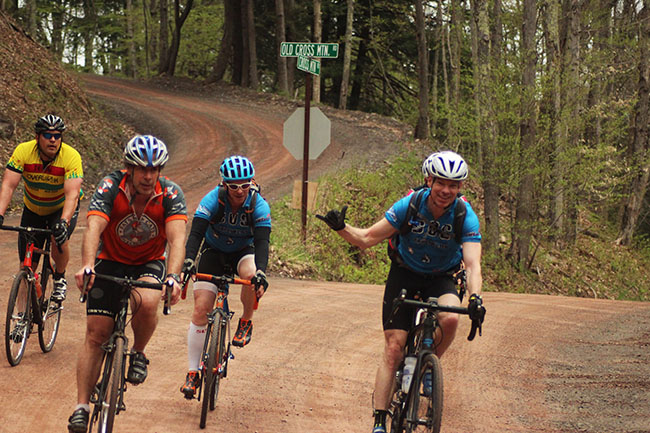 Riders enjoying Cross Mountain Crusher fun on a back road through a wooded area