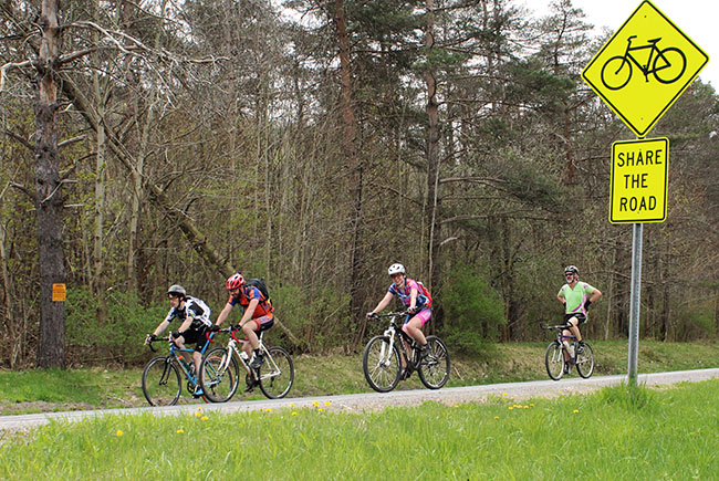 Cyclists easing down a country road past a Share The Road sign